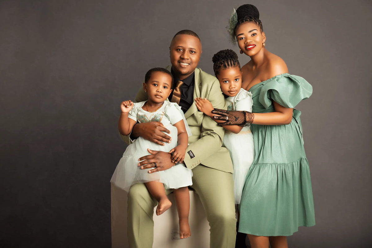 Family of four posing together against a gray background for a family photo shoot in Brackenfell Cape Town