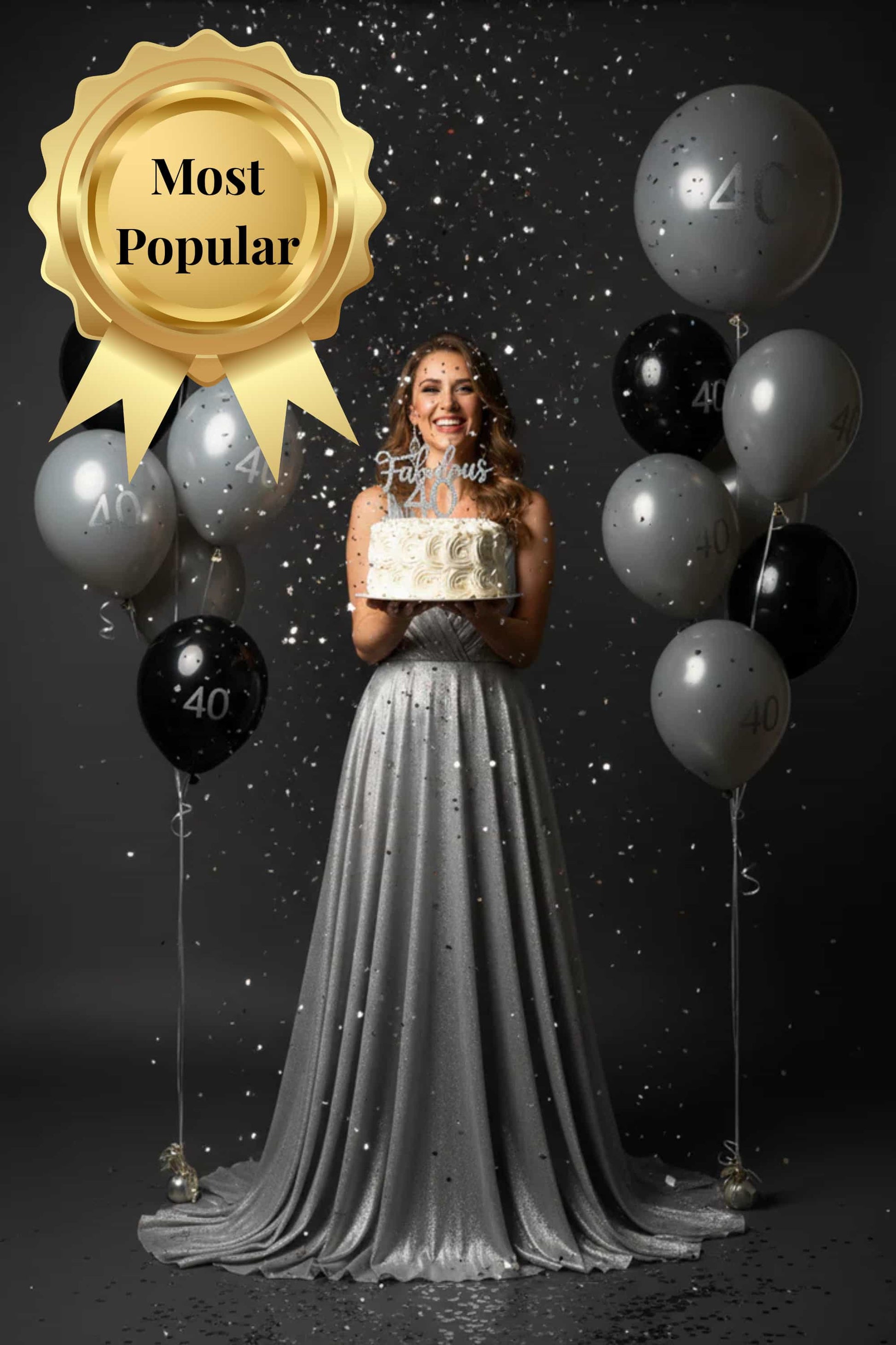 Woman in a silver dress holding a cake with balloons and 'Most Popular' award on a dark background