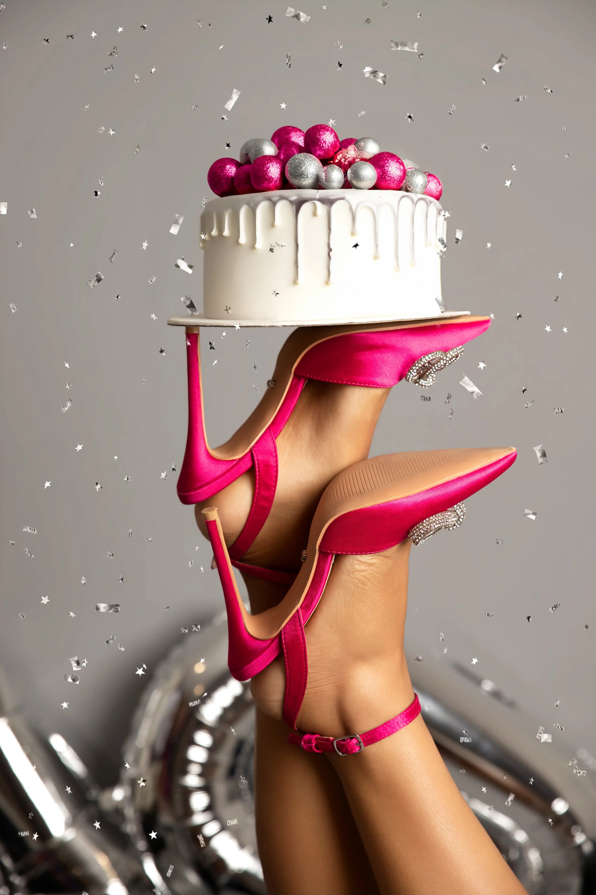 Pink high-heeled shoes holding a small cake with colorful berries on a gray background