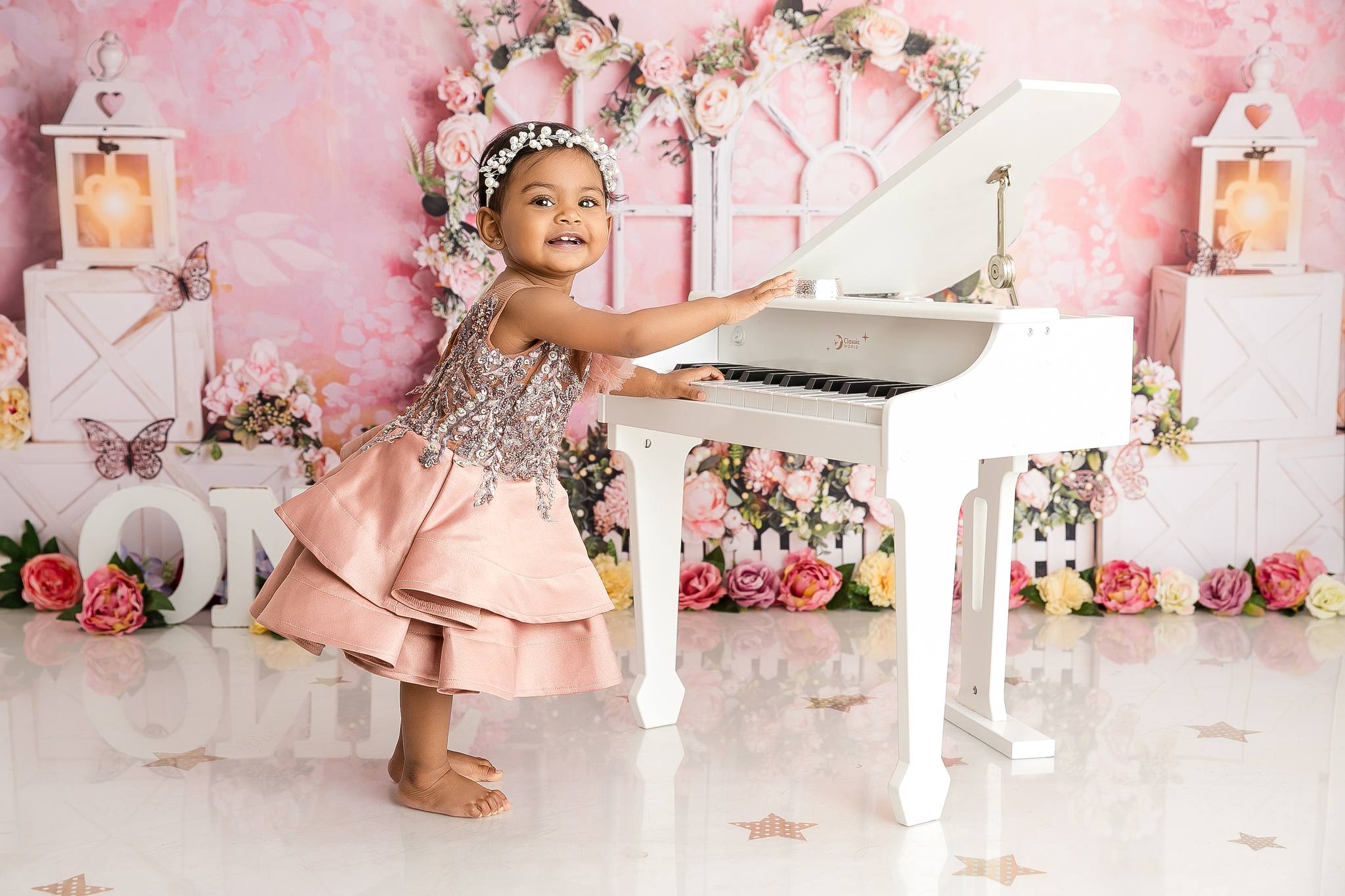 Girl standing next to a piano in a princess dress facing towards the camera with flowers around her