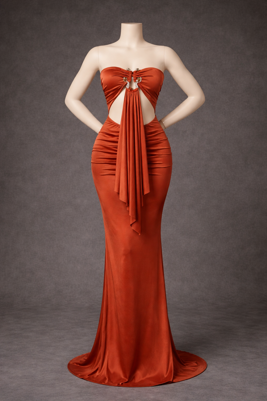burnt orange evening gown on a mannequin against a grey background for a maternity photo shoot
