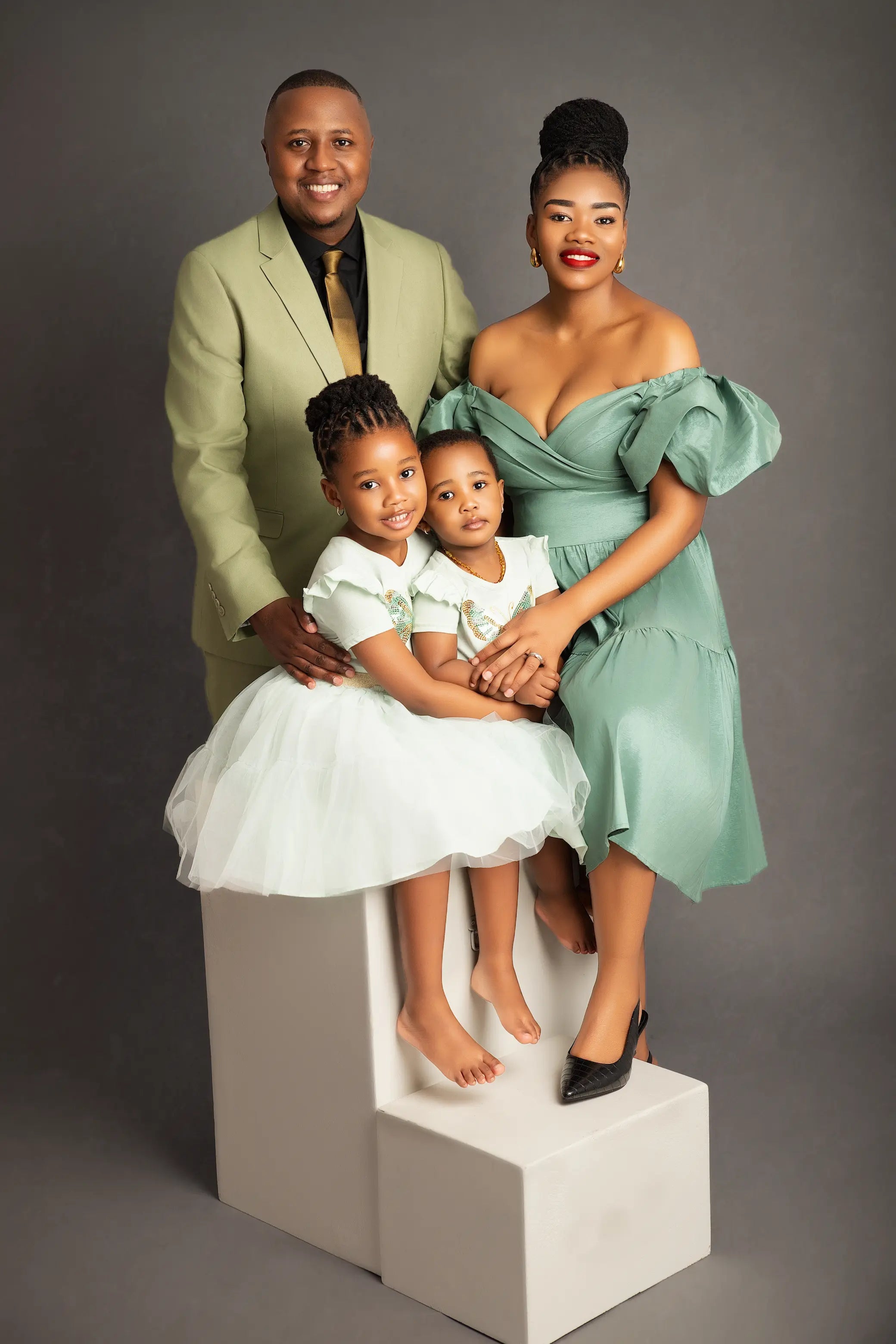 Family of four posing on a gray background