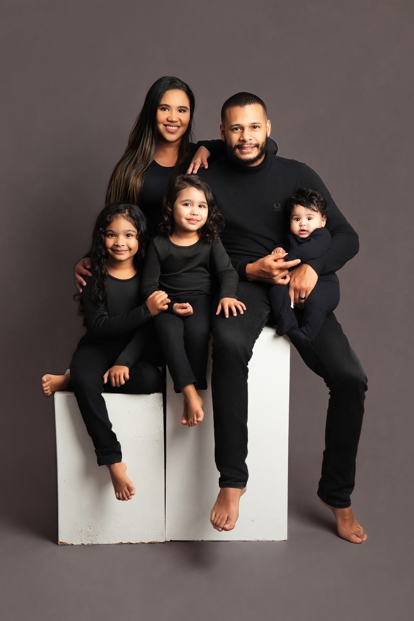 A family of 5 wearing all black against a dark grey background