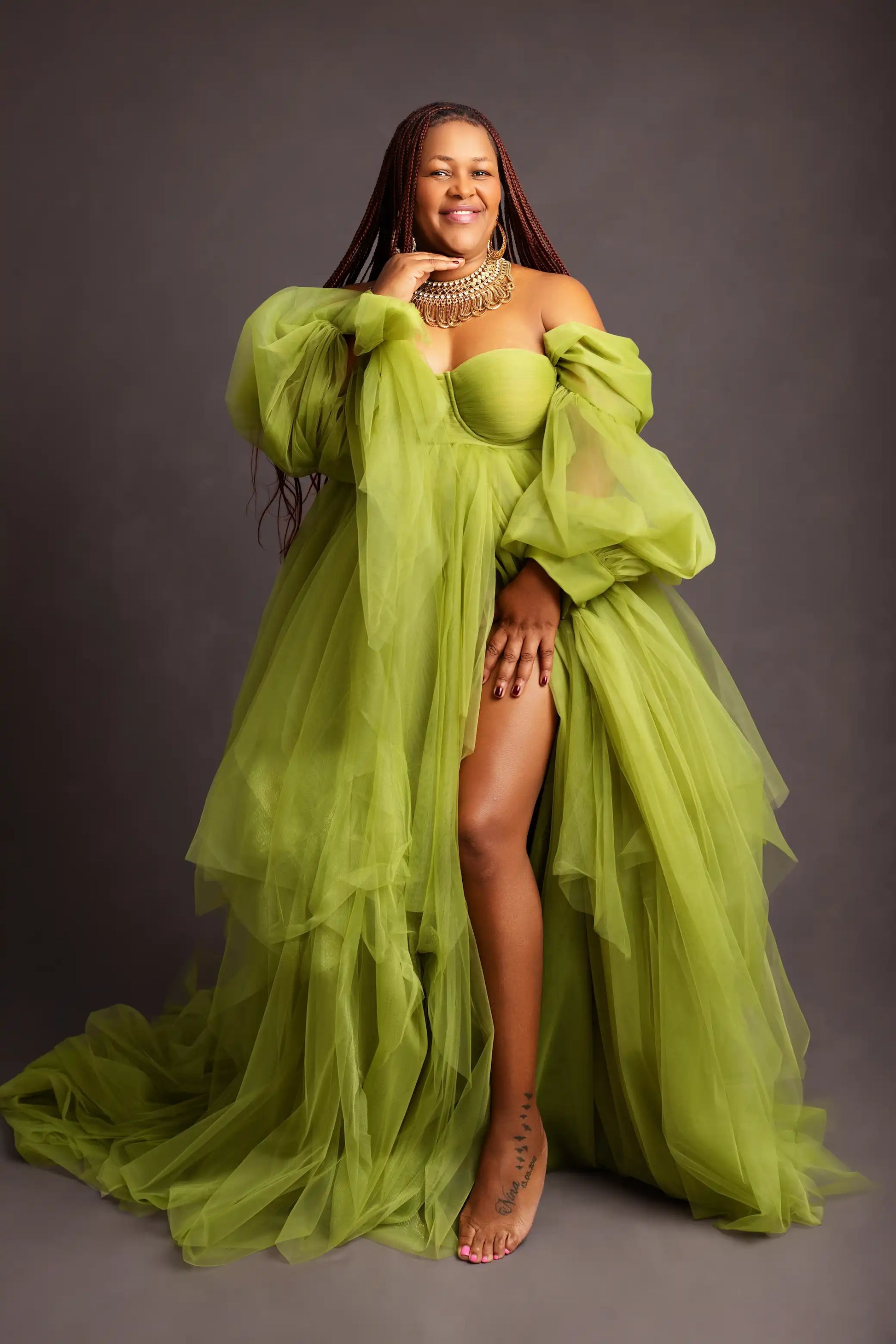 Woman wearing a flowing green dress against a gray background
