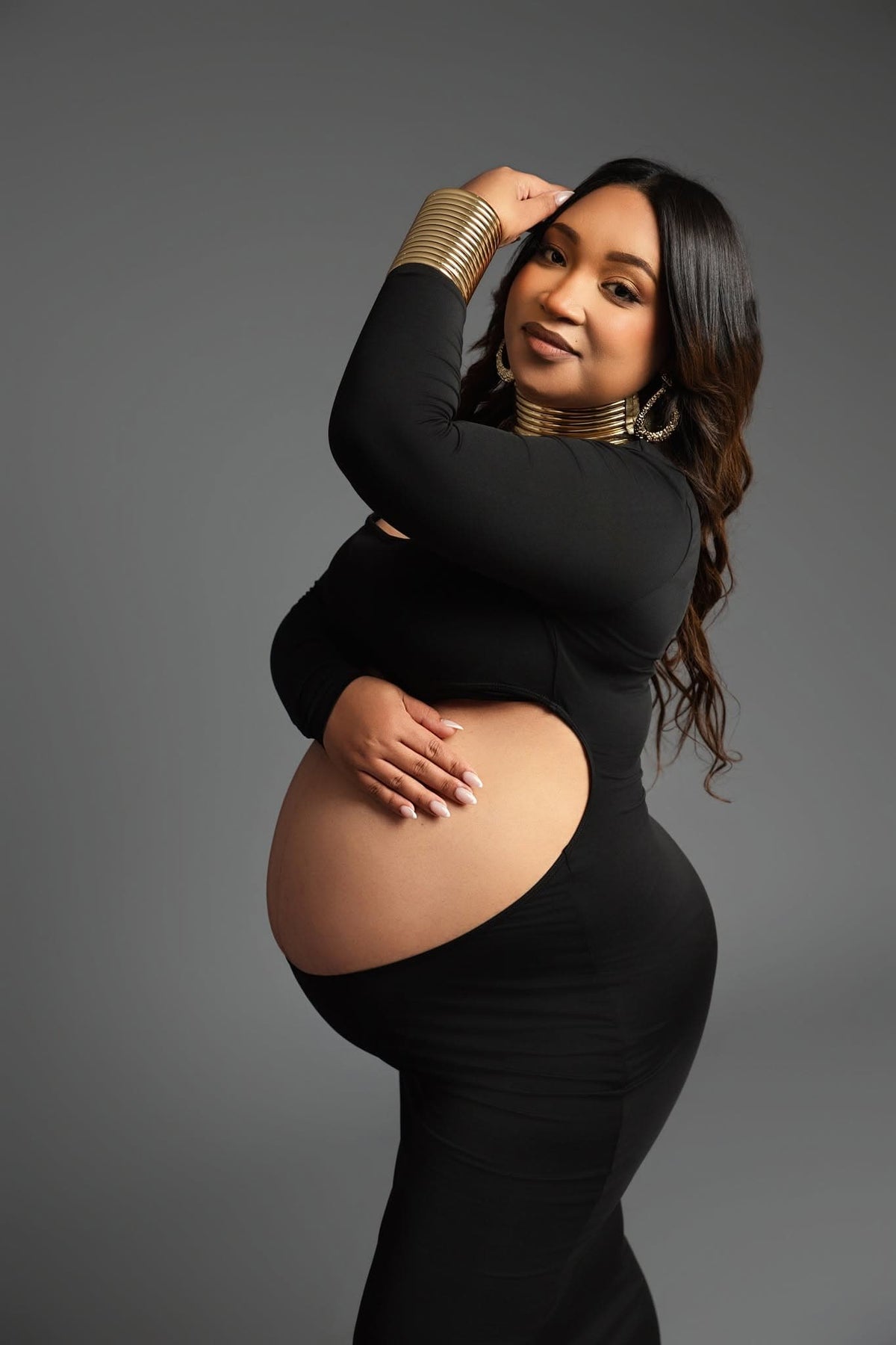 Women dressed in black against a grey background posing for a maternity shoot