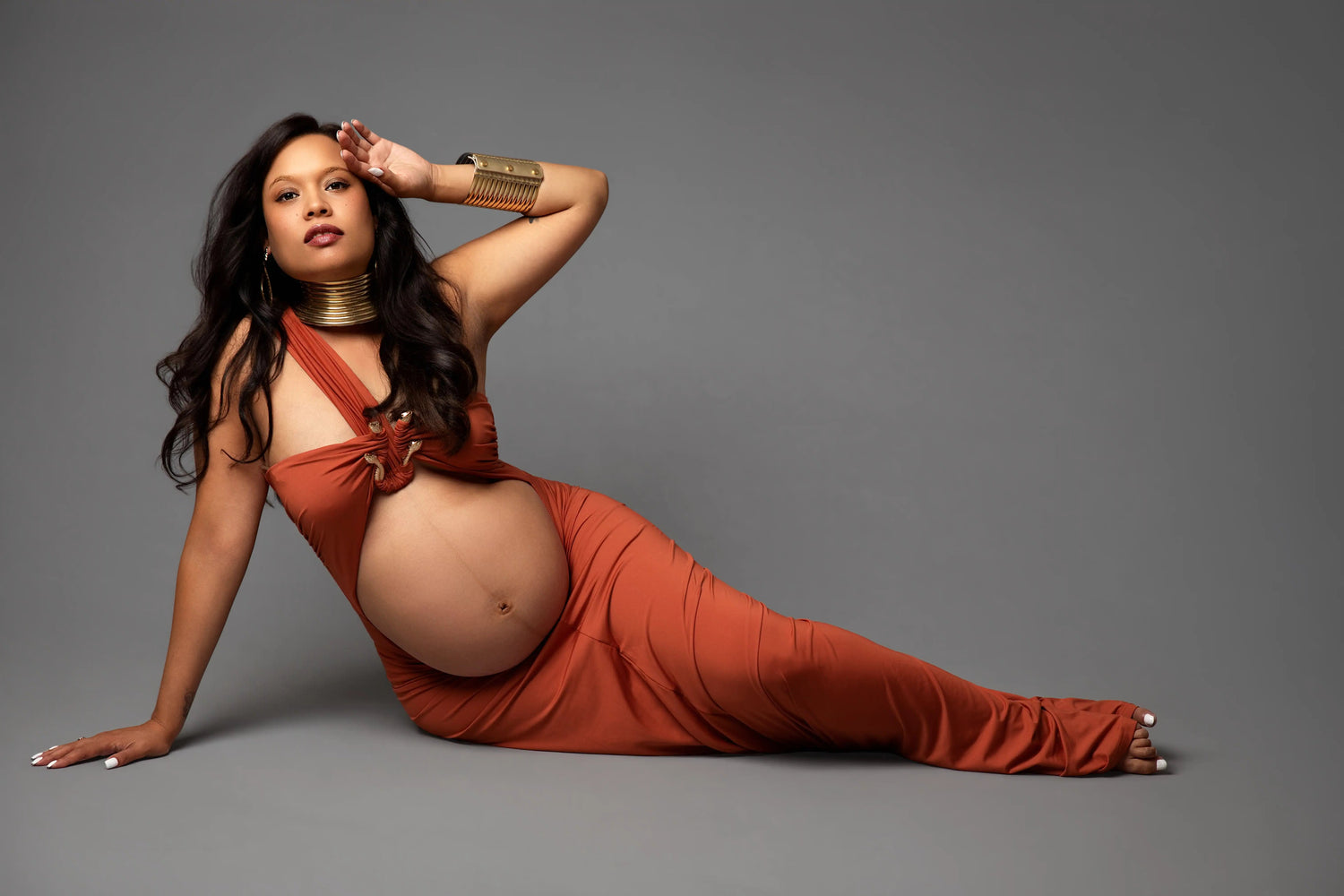 A Maternity Photo Shoot with Mom dressed in a burnt orange dress sitting on the floor