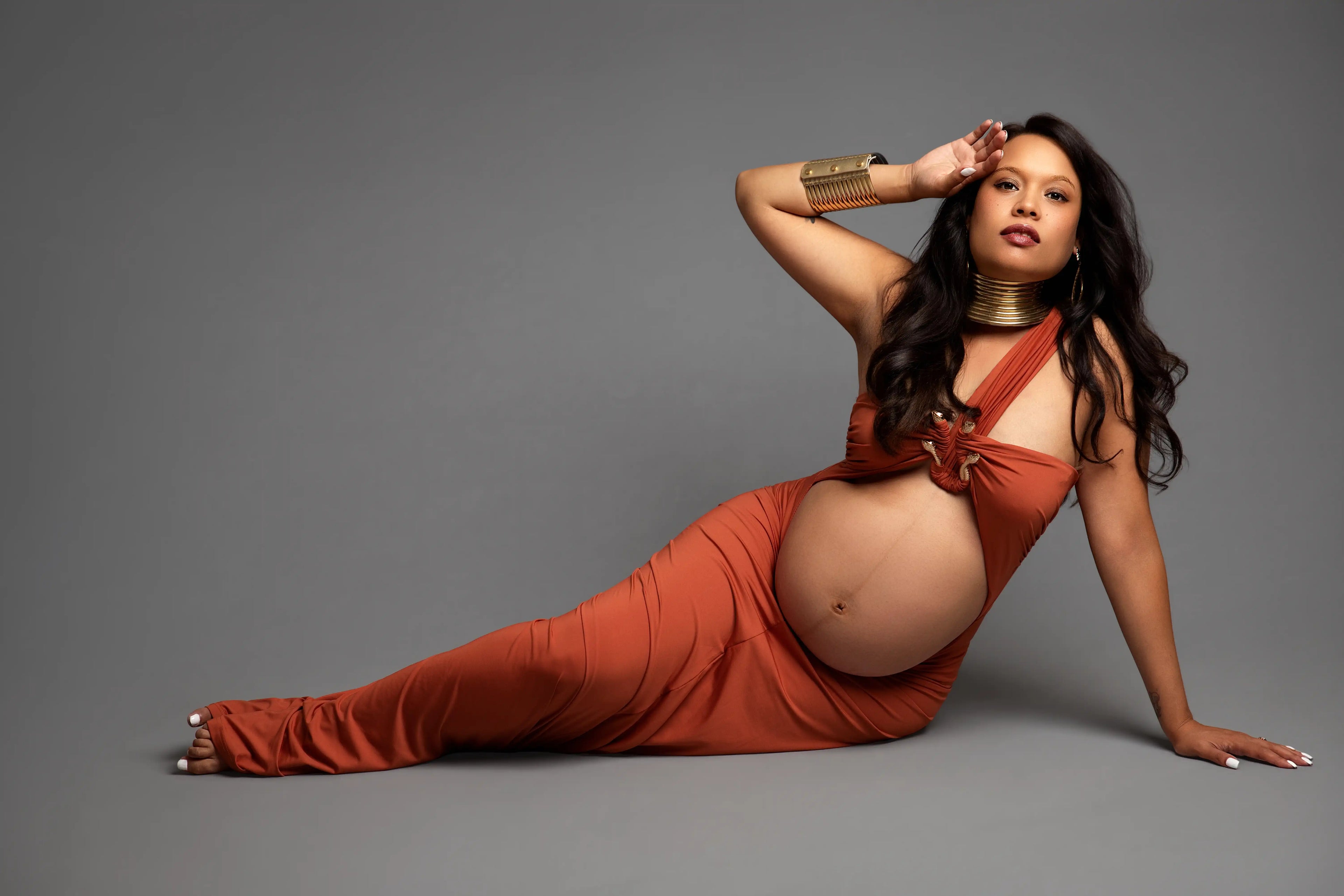A Maternity Photo Shoot with Mom dressed in a burnt orange dress sitting on the floor