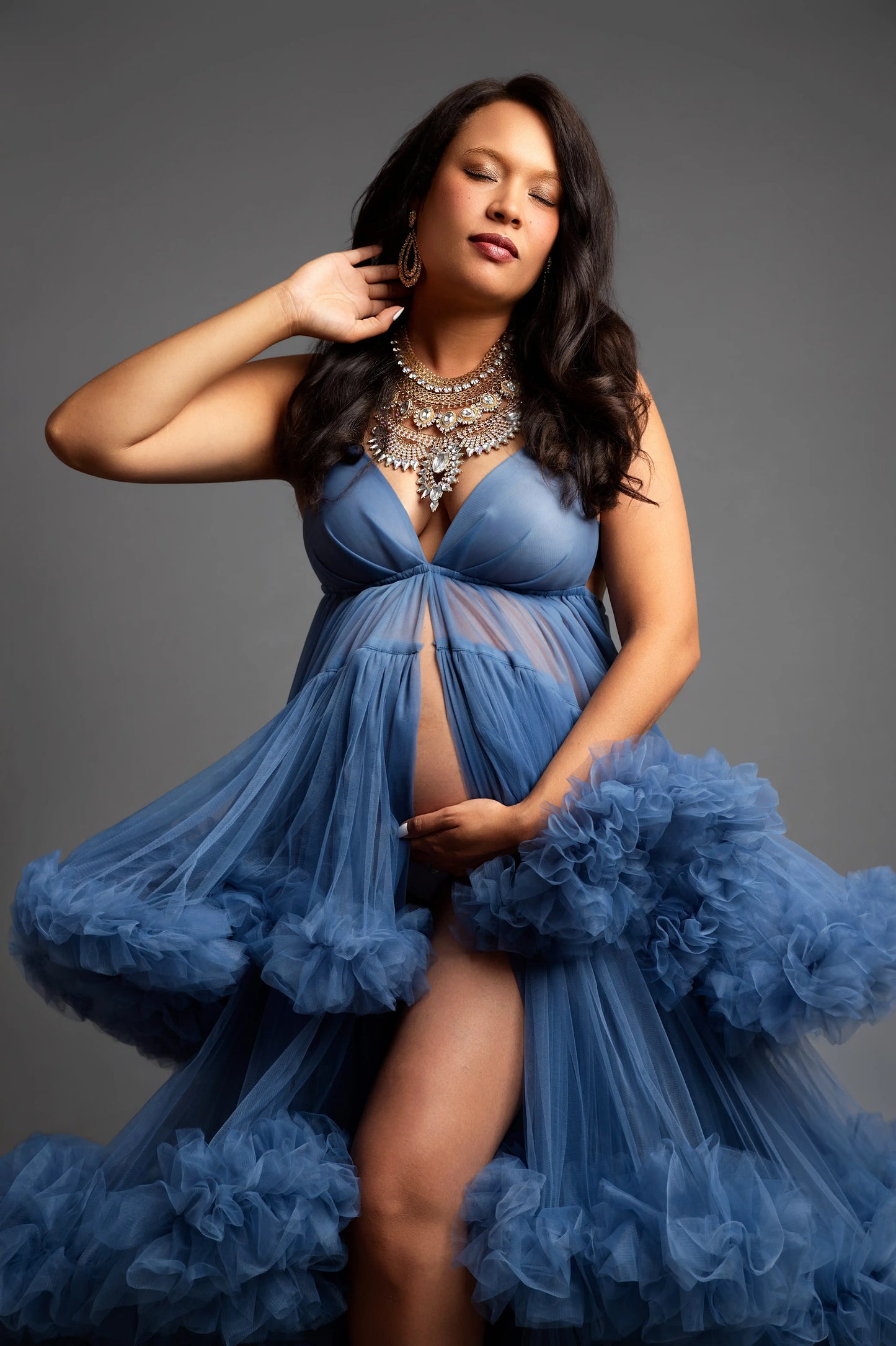 Pregnant woman wearing a blue dress with a gray background