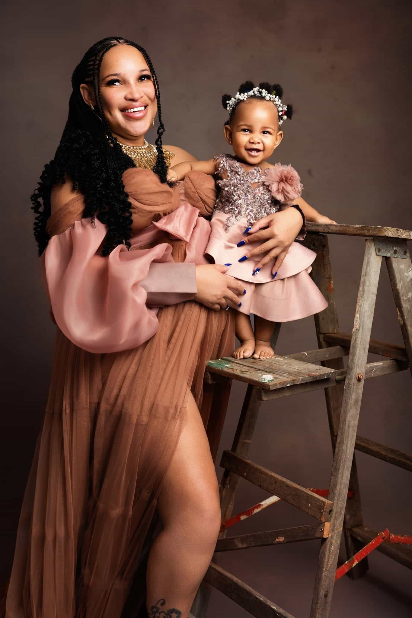 Woman holding a child on a ladder against a brown background