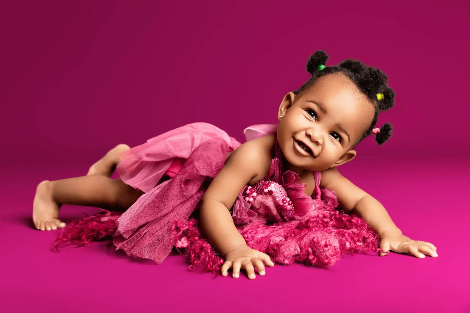 Baby lying on a pink background dressed in pink