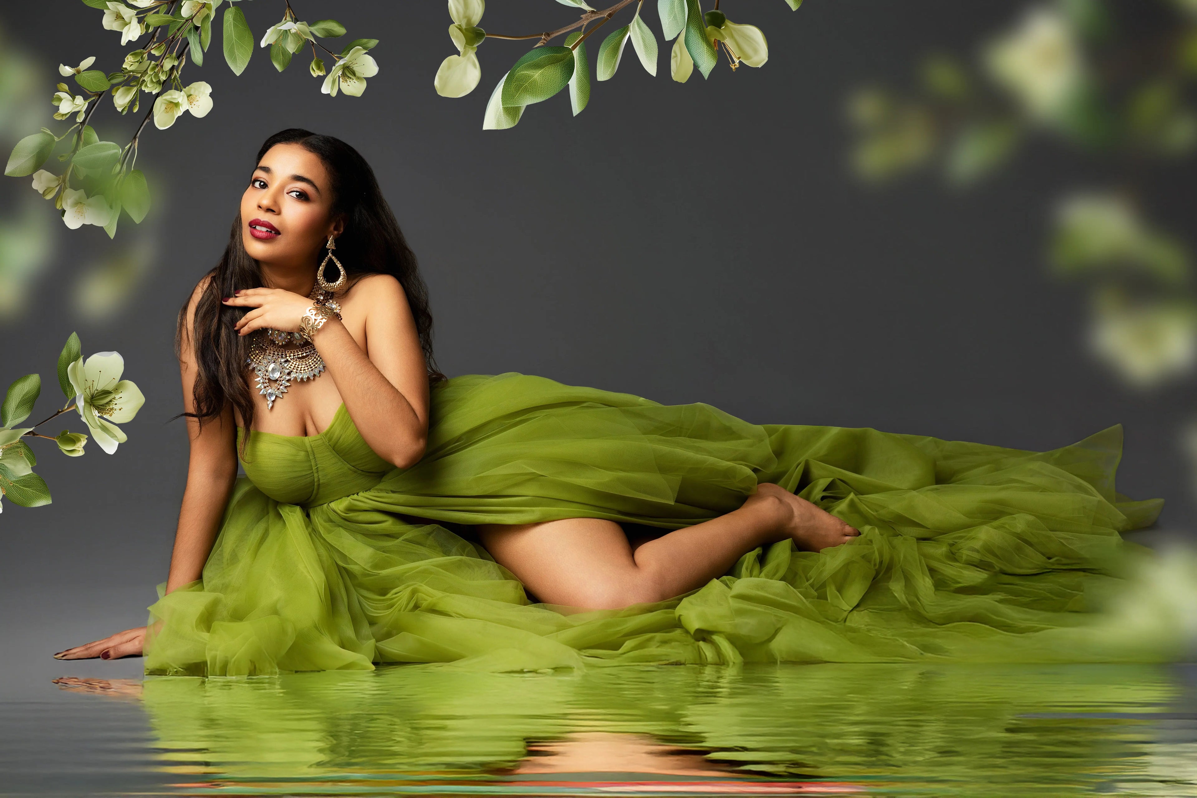 Woman in a green dress sitting on water with floral elements