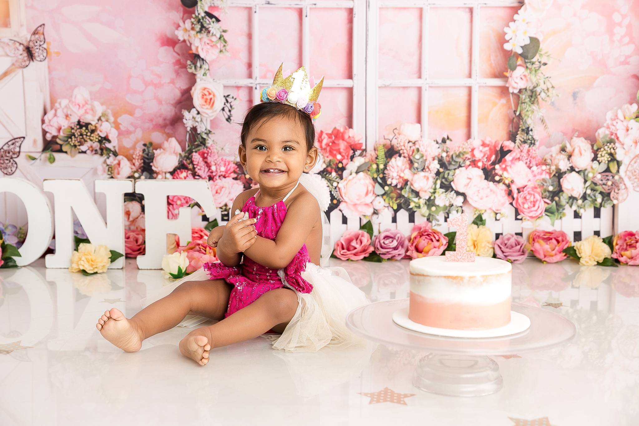 Girl on a floral scene with a cake celebrating her first birthday