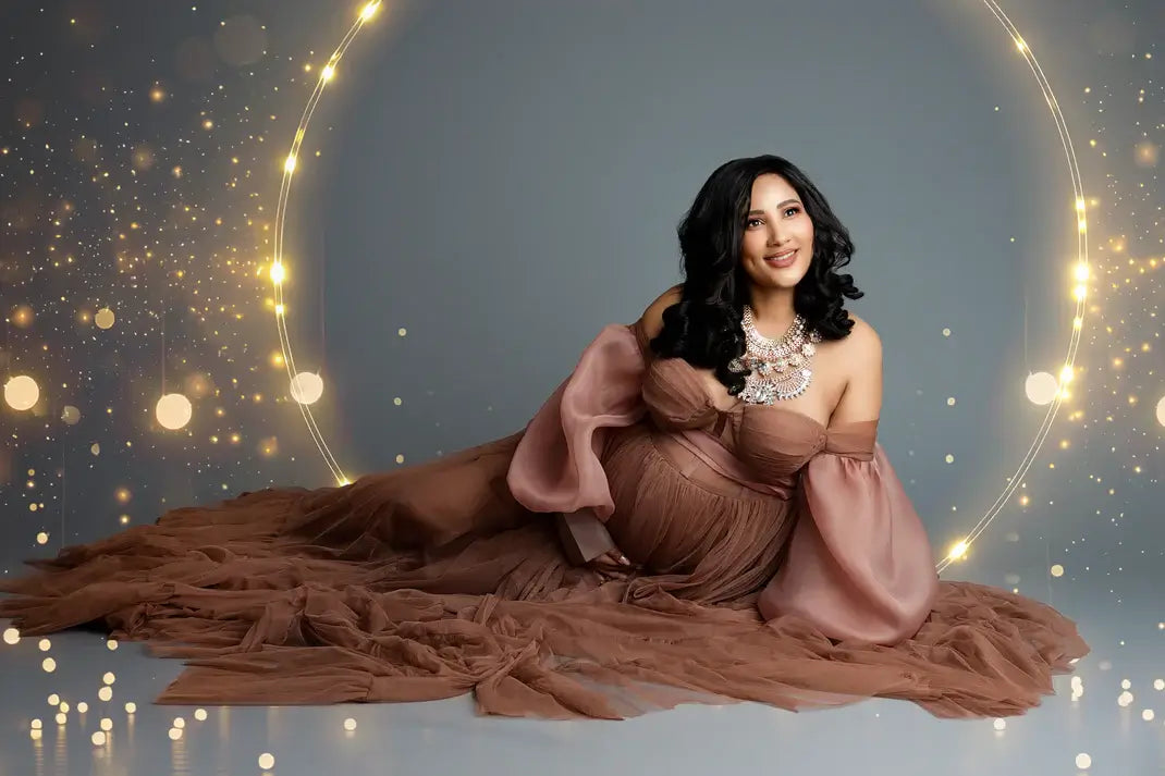 Woman in a long brown dress sitting on a reflective surface with a glowing circular light effect.